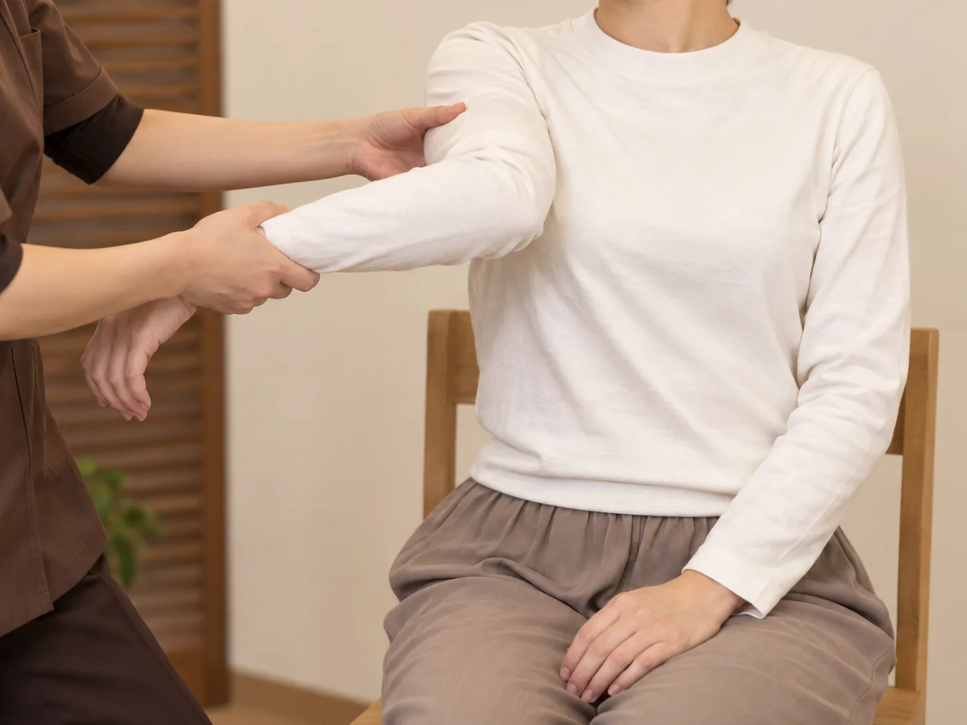 着衣の女性のお客様の肩と腕を支えながら動かすストレッチのイメージ