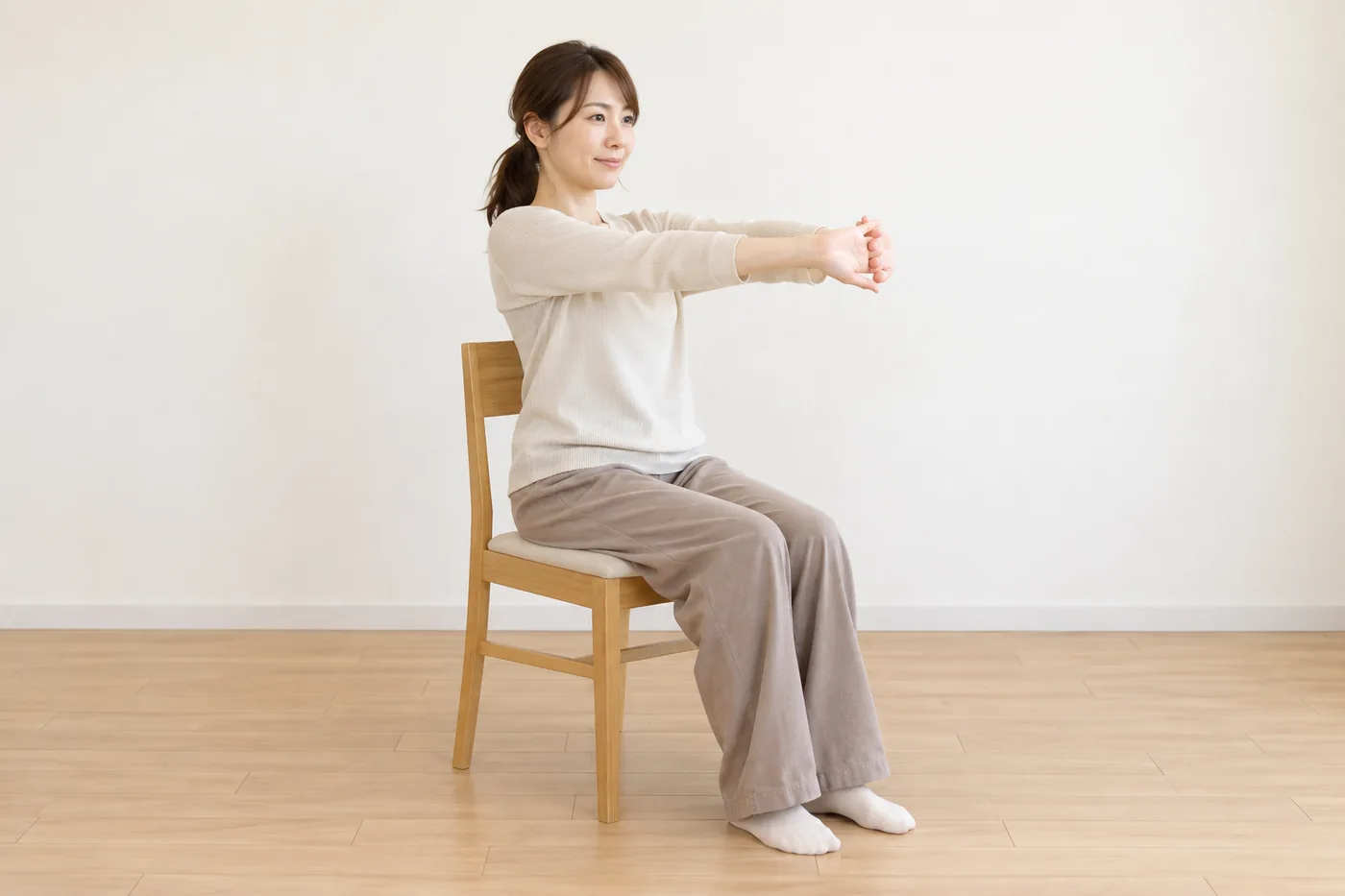 椅子で腕を胸の前へ穏やかに伸ばす女性のイメージ