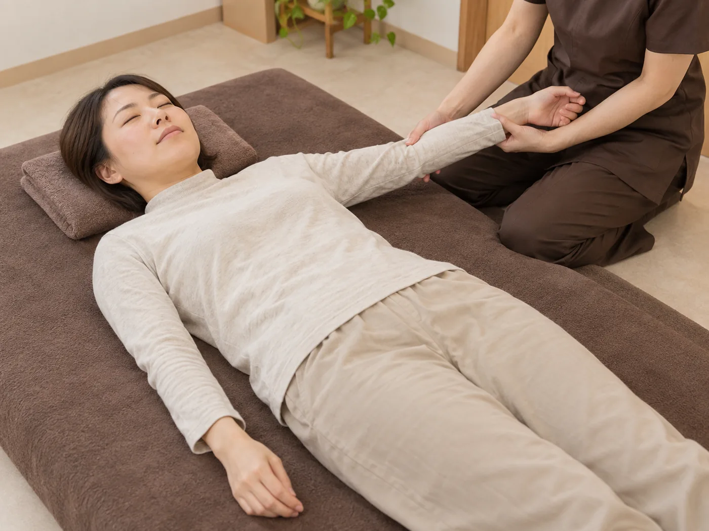 横向きに休む着衣の女性への肩と腕のケアのイメージ